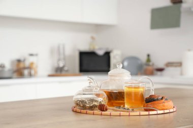 Mutfaktaki masada lezzetli çörekli bitki çayı ile çaydanlık.