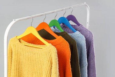 Gri arkaplanda renkli süveter rafı, yakın plan