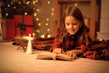 Akşamları evde ekoseyle Noel hikayesi okuyan küçük bir kız.