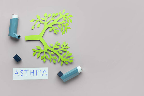Ингаляторы, бумажные легкие и лист бумаги с текстом ASTHMA на сером фоне