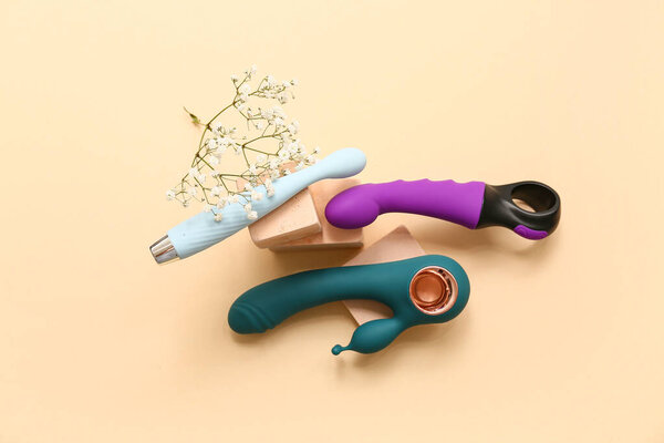 Composition with different vibrators, plaster podiums and flowers on color background