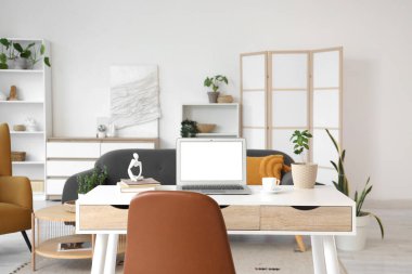 Boş bir dizüstü bilgisayar, kahve fincanı ve oturma odasındaki programcının masasına bitki.