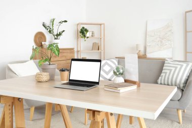 Boş dizüstü bilgisayar, kahve fincanı ve bitkiler oturma odasındaki programcının masasında.