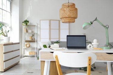 Oturma odasındaki programcının masasında lamba olan boş bir laptop.