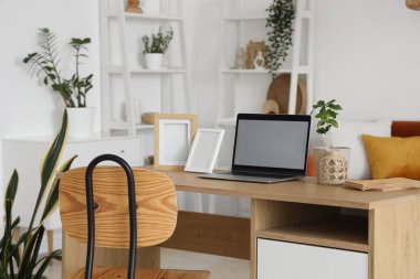 Oturma odasındaki programcının masasında çerçeveleri olan boş bir laptop.