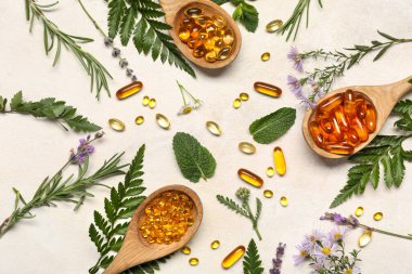 Ahşap kaşık haplar ve hafif arka planda farklı otlar içeren kompozisyon