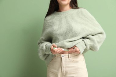 Yeşil arka planda tükenmez kalem kullanan diyabetik genç kadın, yakın plan