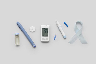 Kalemli glukometre, glikoz sensörü ve arka planda gümüş farkındalık kurdelesi. Diyabet kavramı