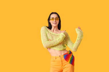 Sarı arka planda dans eden güneş gözlüklü mutlu genç kadın.