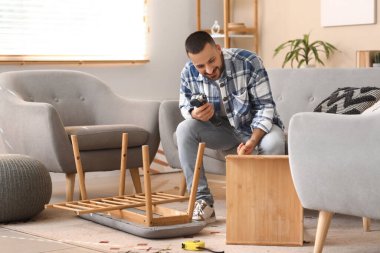 Evinde ahşap masa montajı yapan genç bir adam.