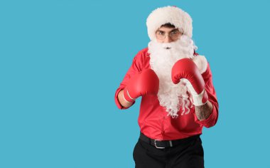 Mavi arka planda boks eldivenli genç Noel Baba