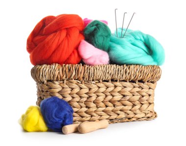 Hasır sepet ve beyaz arka planda farklı yün ve iğneler.
