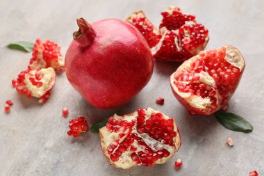 Gri arka planda yaprakları ve tohumları olan taze olgun narlar. Yakın plan.