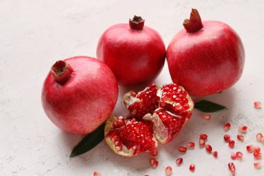 Beyaz zemin üzerinde tohum ve yapraklarla taze olgun nar.