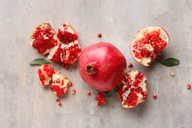 Gri zemin üzerinde yaprakları ve tohumları olan taze nar.