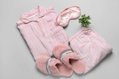 Terlikli çizgili pijamalar, uyku maskesi ve açık arkaplanda bitki.