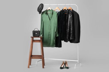 Gri arka planda şık kadın kıyafetleri, aksesuarları ve ayakkabıları var.