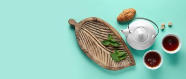 Çay demliği, fincanlar ve turkuaz arka planda kruvasan ile kompozisyon metin için alan, üst görünüm