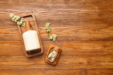 Ahşap arka planda beyaz leylak dalları olan sabun makinesi.