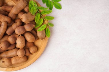 Plate of tasty tamarinds on white background clipart