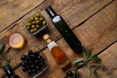 Ahşap zemin üzerinde farklı zeytin ve yağ kadehleri.