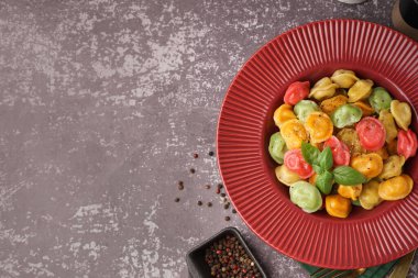 Koyu masada fesleğen ve biberli kaynamış renkli hamur köftesi tabağı.