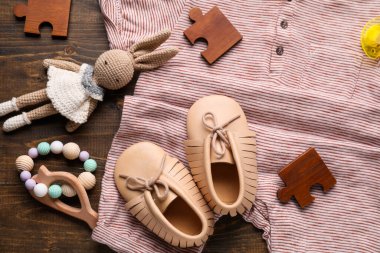 Şık bebek kıyafetleri ve ahşap arka planda aksesuarları olan kompozisyon, yakın plan.