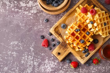 Gri arka planda böğürtlen ve akçaağaç şurubuyla lezzetli waffle tahtaları.