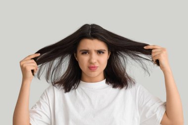 Beyaz arka planda kepek sorunu olan genç bir kadın.