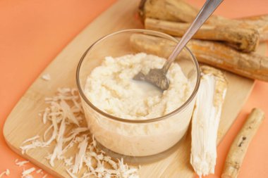 Turuncu arka planda yabanturpu kökü ve kaşıkla cam kasede yabanturpu sosu.