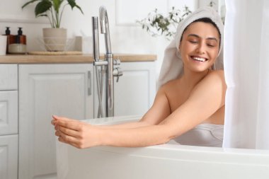 Perdeli gülümseyen genç kadın evde banyo yapıyor.