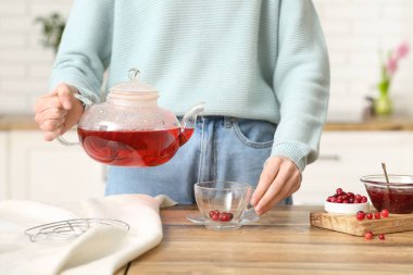 Genç bayan mutfakta yabanmersinli çay yapıyor.
