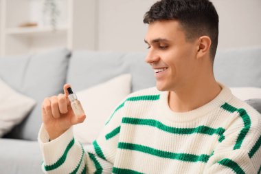 Evinde bir şişe CBD yağı olan genç adam, yakın plan.