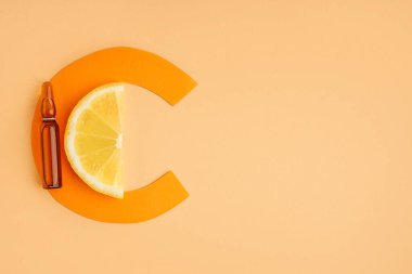 Renk arkaplanına C vitamini, limon dilimi ve C kağıt harfi ampülü