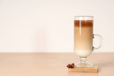 Cam bardak buzlu latte ve bej masada yıldız anason.
