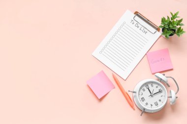 Pembe zemin üzerinde metin hedefleri, yapılacaklar listesi ve alarm saati olan yapışkan bir not