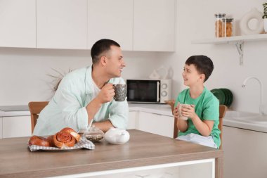 Babasıyla küçük şirin bir çocuk mutfakta çay içiyor.