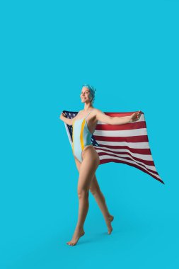 Mavi arka planda ABD bayrağı taşıyan profesyonel genç bayan yüzücü.