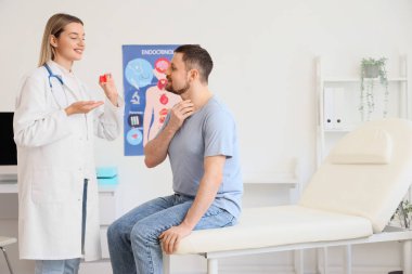 Kadın endokrinolog, tiroit bezini klinikte erkeğe gösteriyor.