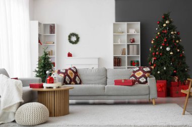 Oturma odasının içinde kanepeler, Noel ağaçları ve raf üniteleri var.