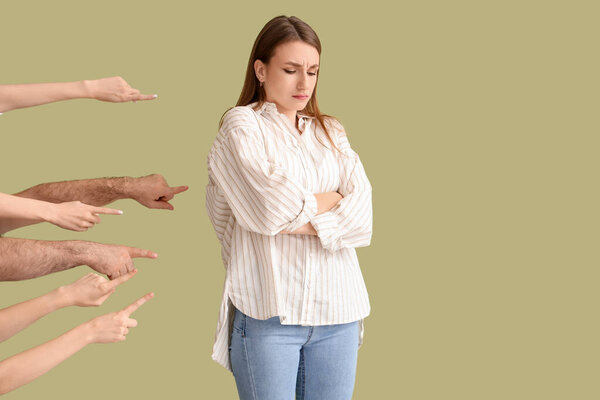 People pointing at sad young woman on green background. Accusation concept