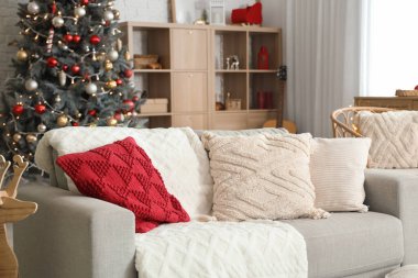 Noel için dekore edilmiş oturma odasının içinde raf ünitesi ve kanepe var.