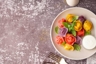 Bir tabak kaynamış renkli hamur köftesi ve fesleğen ve ekşi krema.