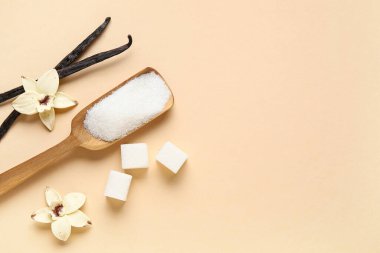 Aromatik vanilya şekerli ahşap kepçe, çiçekler ve bej arka planda çubuklar.