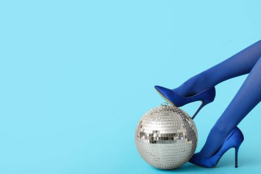 Moda yüksek topuklu kadın bacakları ve mavi arka planda disko topu.