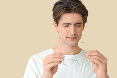 Bej arka planda gözlüklü genç adam, yakın plan. Glaucoma farkındalık ayı