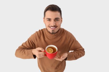 Beyaz arka planda bir fincan limon çayı olan genç adam.