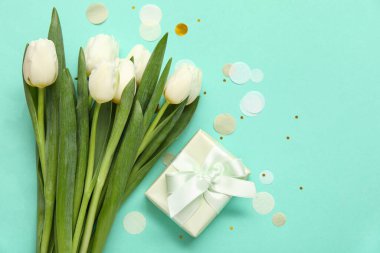 Hediye kutulu beyaz laleler ve turkuaz arka planda konfeti.