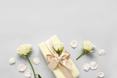 Beyaz arka planda güller ve taç yaprakları olan hediye kutusu