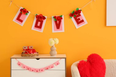 İçinde kiraz çiçekleri olan çekmeceler, hediye kutuları ve turuncu duvarın yanındaki çiçekler. Sevgililer Günü kutlaması